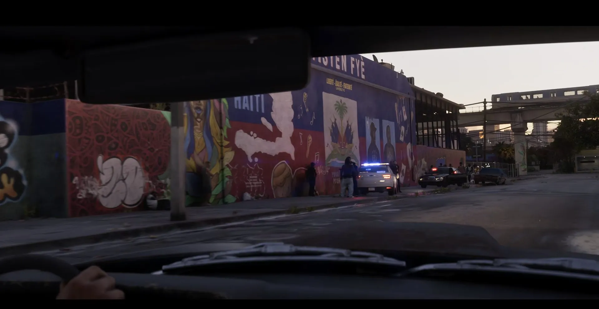 A street of murals and a HAITI sign seen through a windshield